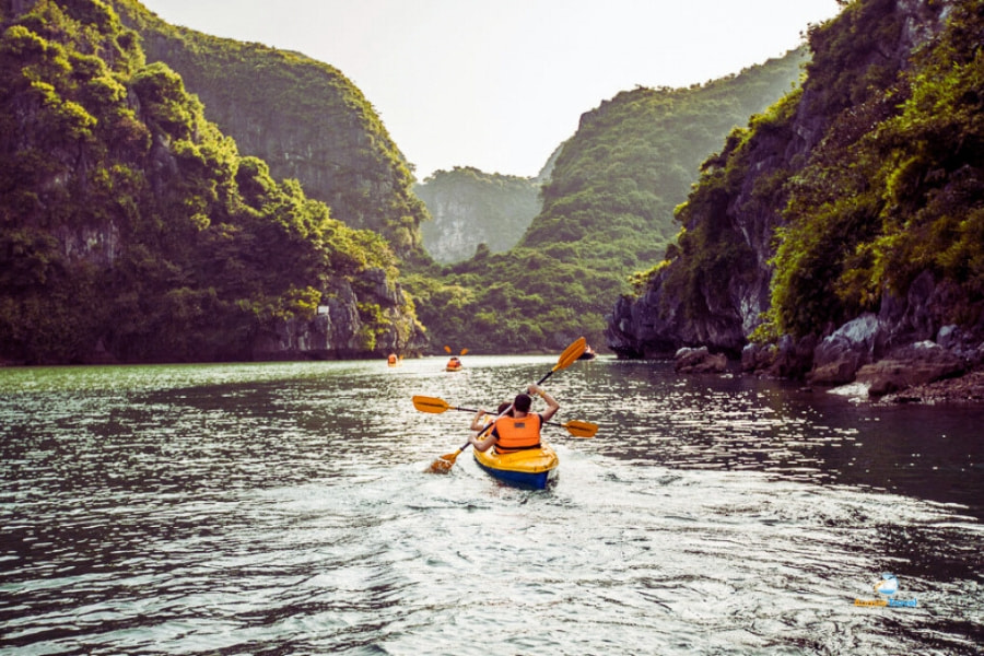 Travelers kayaking between limestone cliffs Halong Bay – Auasia Travel